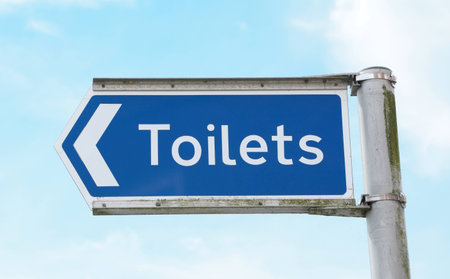 Signpost on a metal pole pointing left towards public toilets