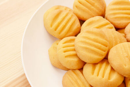 Close up of a pile of delicious yellow biscuits, served on a white plateの写真素材