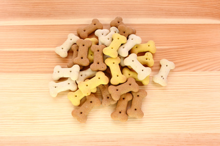 Heap of dried dog biscuits on a wood grain backgroundの写真素材