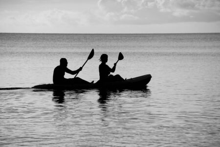 Man and woman silhouetted at sea in a kayak - monochrome processingの写真素材