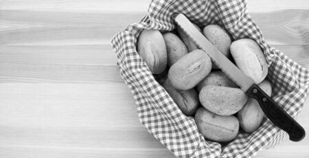 Basket of bread rolls and a knife on a wooden background with copy space - monochrome processingの写真素材