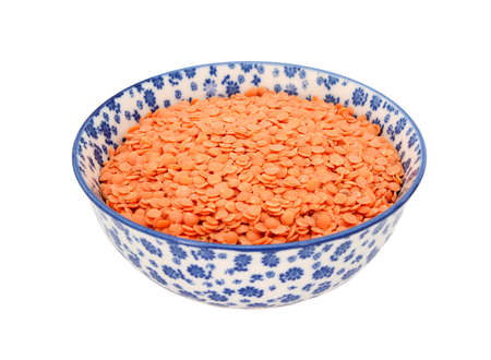 Red lentils in a blue and white porcelain bowl with a floral design, isolated on a white backgroundの写真素材
