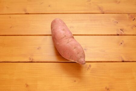 One raw sweet potato on a wooden tableの写真素材