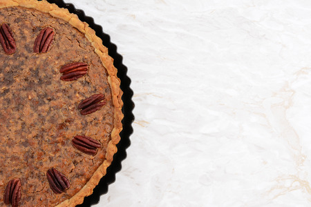 Freshly baked pecan pie in the baking tin, copy space on the kitchen worktop