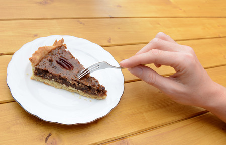 Woman's hand holding fork to cut into a slice of traditional pecan pieの写真素材