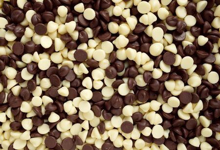 Mixture of white and dark chocolate chips as an abstract background textureの写真素材