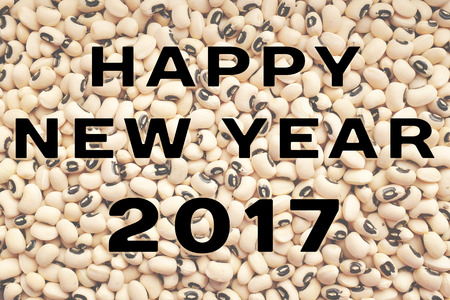 HAPPY NEW YEAR 2017 text written over a dried black eyed beans background, food considered to bring...