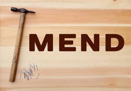 Hammer and metal panel pins with MEND concept written on a wooden backgroundの写真素材