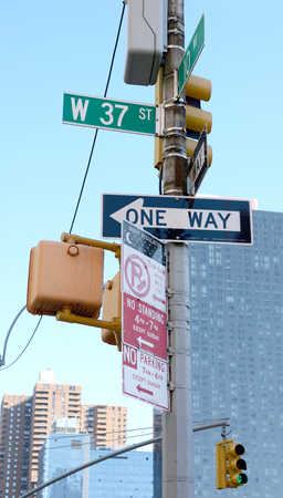 Collection of street signs at West 37th Street and 10th Avenue in New York City, with traffic lights beyondのeditorial素材