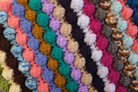 Bobble crochet stitches in diagonal stripes, multi-coloured yarn as abstract background texture
