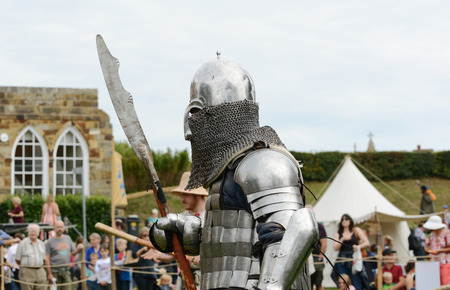 TONBRIDGE, ENGLAND - SEPTEMBER 9, 2018: Medieval knight in battle armour, carrying a pole arm weapon, at the Medieval Fair at Tonbridge Castleのeditorial素材