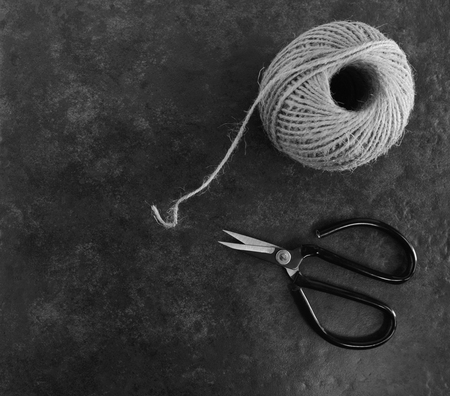 Ball of twine with traditional flower scissors on dark grey background with copy space - monochrome processingの写真素材