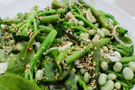 Tasty spring salad of baby broccoli, asparagus, broad beans, spinach leaves and shallot dressed with sesame and nigella seedsの写真素材