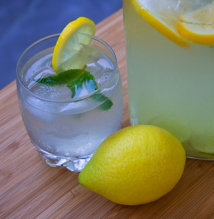Glass of cold homemade lemonade,lemon and pitcher of lemonadeの写真素材