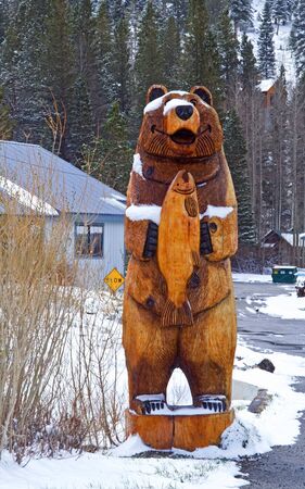 Sculpture of wooden bear with fish near fishermanの写真素材