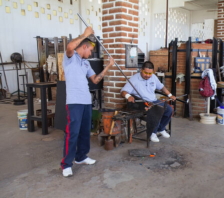 Cabo San Lucas, MEXICO - April 8 2014 - Two an unidentified glass blowers show how to blow glass at glass blown factory on  April 8 2014  in Cabo San Lucas, Mexico.のeditorial素材