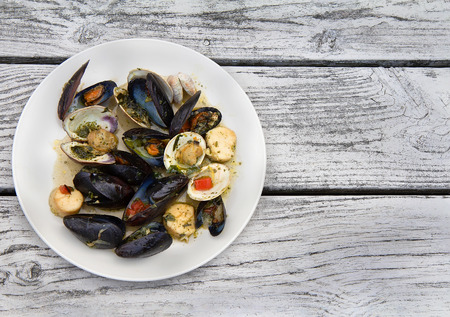 Plate with Seafood Bruschetta (Mussels, Clams and Scallops) at weathered wood background. Flat lay.の写真素材