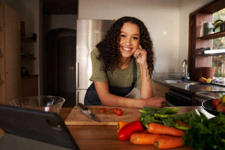 Portrait of multi-cultural female smiling in her modern kitchen. Happy, healthy and confident at homeの写真素材