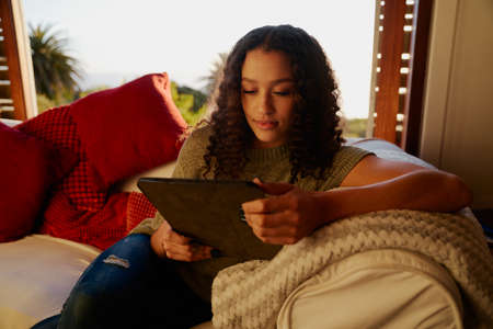 Multicultural young adult female centent while watching screen of electronic tablet. Modern...