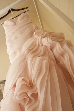A pink wedding dress hangs from a four poster bead  の写真素材