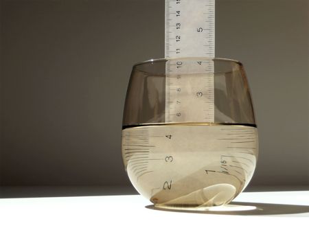 glass half full or half empty of water with rulerの写真素材