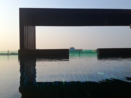 Swimming pool canopy and blue sky with reflection in water. Taken with mobile phone camera.