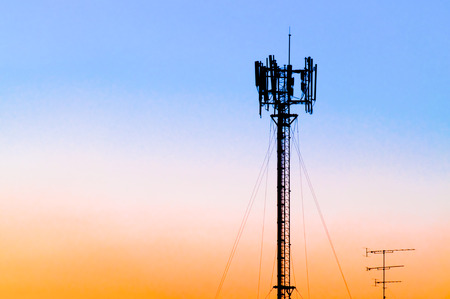 Silhouette of cellular tower against blue, pink and orange sunset sky. Also known as cell site or cell tower is where antennae and equipment are placed. Correct term is Base Transceiver Station.の写真素材