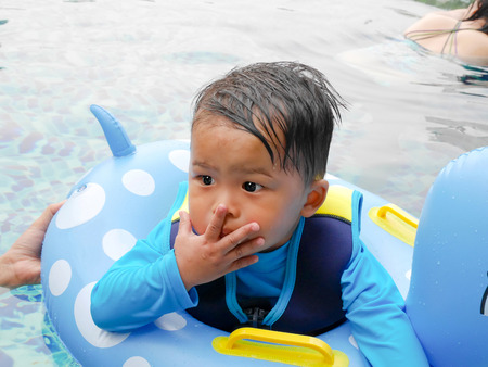 Little boy in swimming pool with surprised face