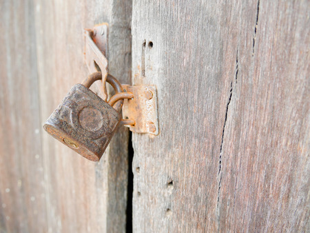 Old rusty padlock on wooden door backgroundの写真素材