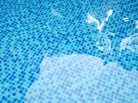 Blurred distortion of tiles and trees reflection in swimming pool
