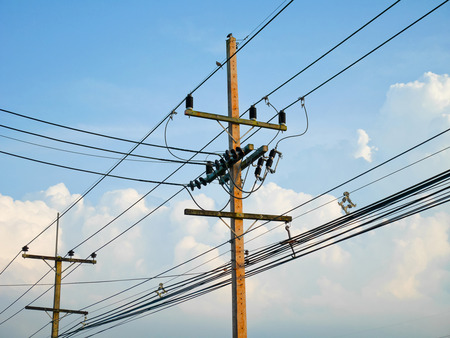 Utility poles supporting wires for various public utilities on blue sky background