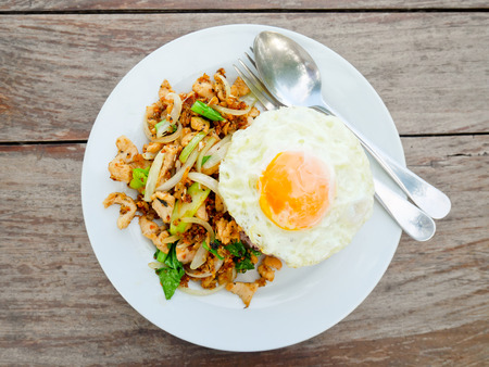 Fried chicken with garlic and pepper served with brown rice and fried egg on topの写真素材