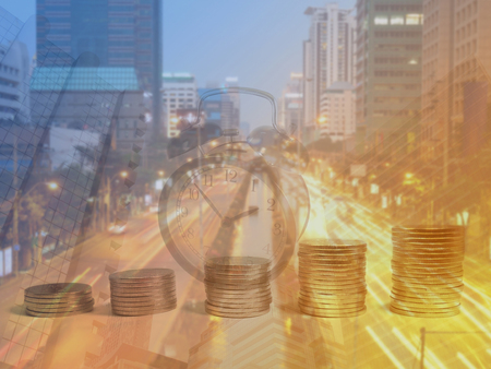 Double exposure of coins, alarm clock, buildings and road at dusk in financial district. Finance and...