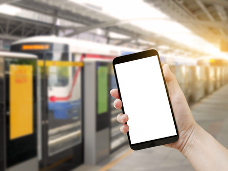 Hand holding blank mobile phone on railway station backgroundの写真素材