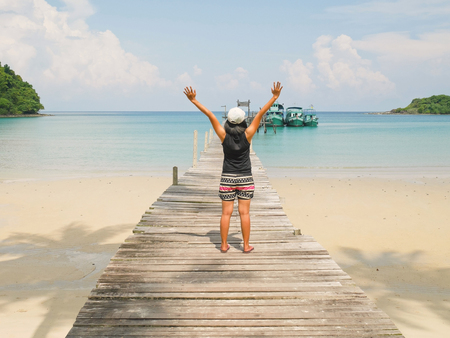 Woman raising hands on wooden jetty on a sunny dayの写真素材
