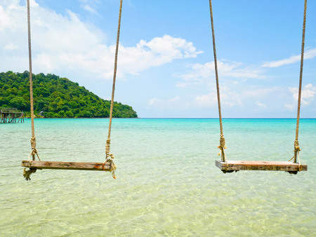 Wooden swings hanged above the seaの写真素材