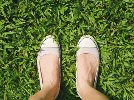 Woman's feet in slip-on shoes standing on the lawnの写真素材