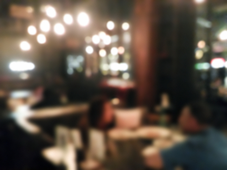 Blurred people dining at restaurant with colorful bokeh light backgroundの写真素材