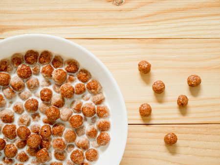 Chocolate cereal balls with milk in a bowl on wooden background. Healthy breakfast concept. Top view.の写真素材