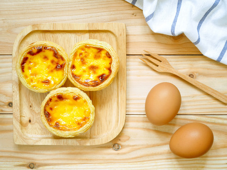 Fresh baked egg tarts or custard tarts (pastel de nata) on wooden plate
