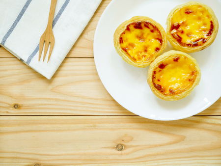 Fresh baked egg tarts or custard tarts (pastel de nata) on a white plateの写真素材