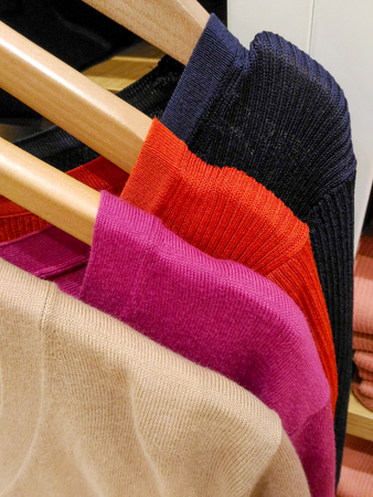 Colorful knitted clothing hanging in boutique shop in shopping mall