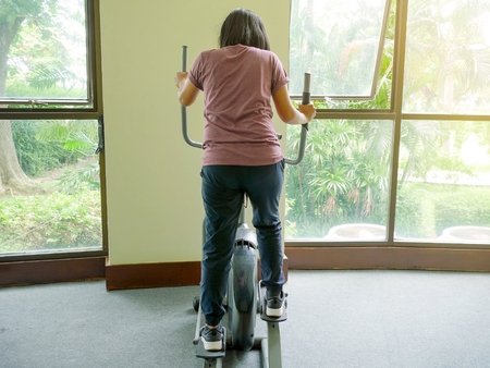 Woman working out on elliptical cross trainer exercise machine at the gymの写真素材