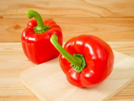 Red bell peppers or sweet peppers or capsicums on wooden cutting boardの写真素材