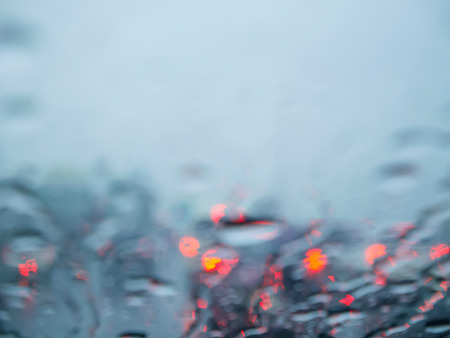 Blurred rain on car windscreen or windshield with bokeh light background from the traffic