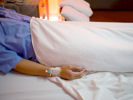 Patient lying in bed with IV extension set on his wristの写真素材
