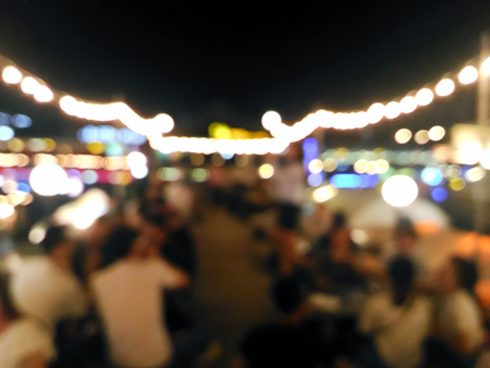 Blurred customers dining at outdoor restaurant with colorful bokeh light in the eveningの写真素材