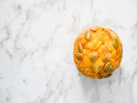 Pumpkin muffin topped with pumpkin seeds on the tableの写真素材
