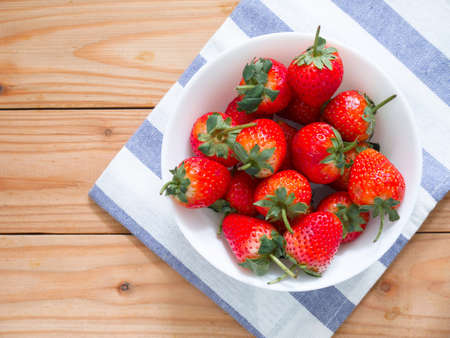 Fresh strawberries in a bowl on wooden tableの写真素材