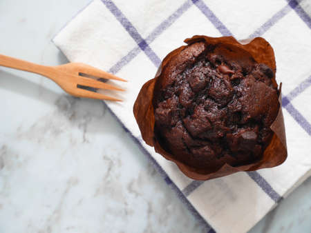Chocolate muffin on dishtowel with wooden fork